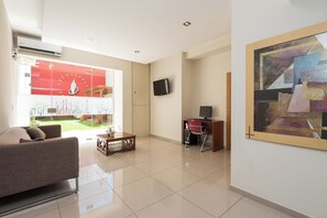 A modern living room with a sofa, a coffee table, and a TV. There is a large window with a red design and a painting on the wall. - Apart Hotel Independencia - Luz y Fuerza (Buenos Aires)