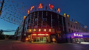 A hotel with a curved facade, illuminated signage, and a clear entrance. - Ronghexin Hotel (Ulan)
