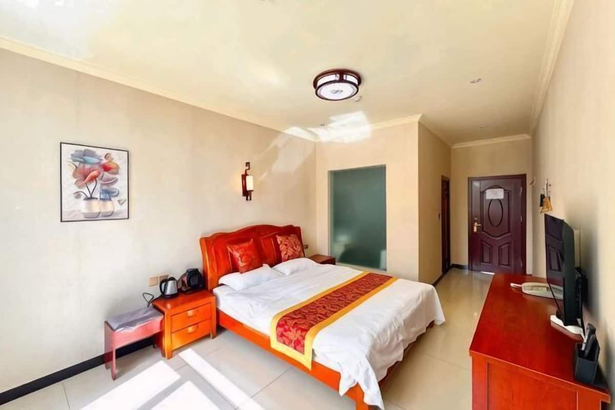 A bedroom with a bed, bedside table, lamp, and a television.