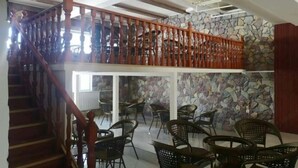 A staircase with wooden balusters leading to a second-floor balcony with wicker chairs and a stone wall. - Ronghexin Hotel (Ulan)