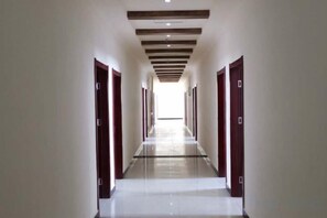 Un long couloir étroit, avec des portes des deux côtés menant à différentes pièces. Le couloir est doté d’un plancher poli et d’un plafond pourvu d’un éclairage encastré.