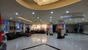A spacious lobby with a chandelier, sofas, a reception desk, and a large vase. - Ronghexin Hotel (Ulan)