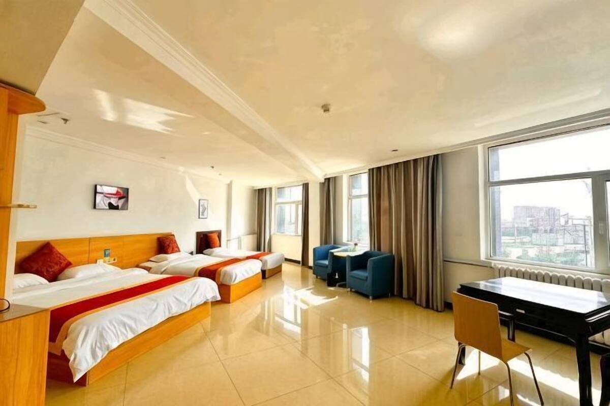 A hotel room with two beds, a desk, and a view of the city.