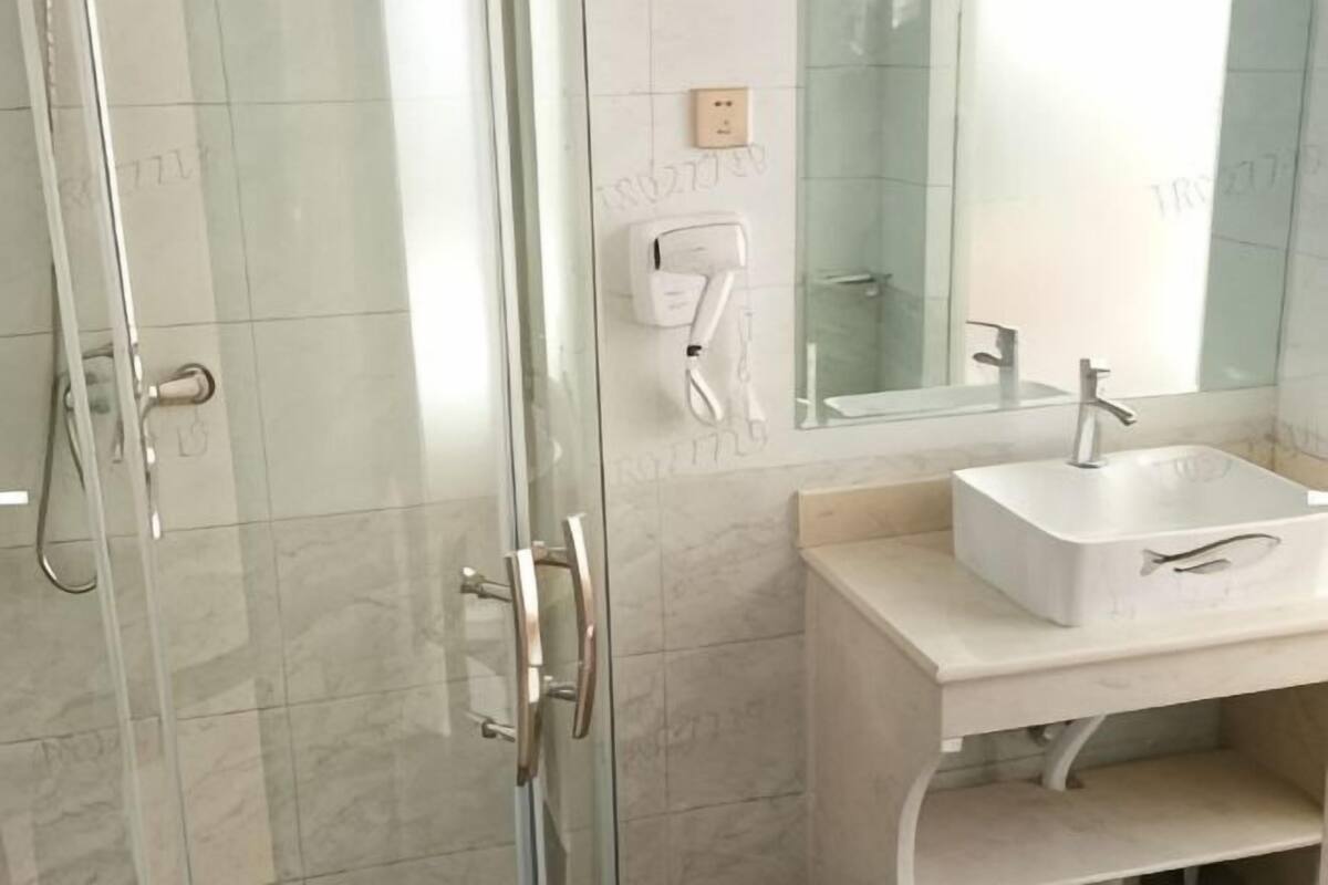 A bathroom with a glass shower enclosure, a white sink, and a mirror.