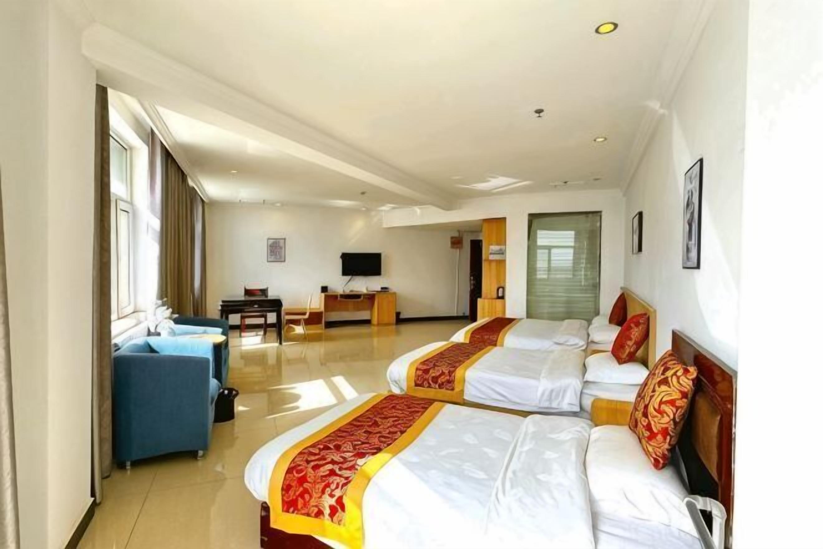 Habitación de hotel con dos camas, un escritorio, una silla, un televisor y un sofá.