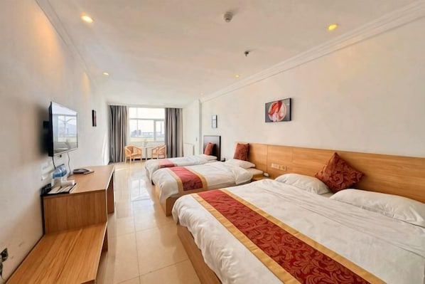 Habitación de hotel con dos camas, un escritorio, un televisor y ventana con vistas.