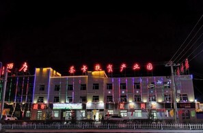 A building with illuminated signage and multiple storefronts at night. - Ronghexin Hotel (Ulan)