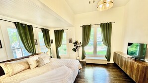 Une chambre avec un grand lit, un banc, une télévision et une vue sur l’extérieur.