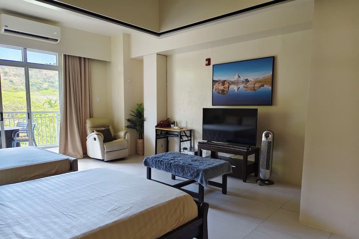 Ein Hotelzimmer mit zwei Betten, einem Fernseher, einem Schreibtisch und einem Balkon mit Blick.
