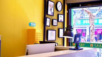 A reception desk with a computer, a lamp, and framed pictures on the wall.