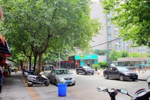 A street with parked scooters, cars, and a blue trash bin. - Jitai Hotel (Shanghai Dahua 3rd Road Subway Station) (Shanghai)