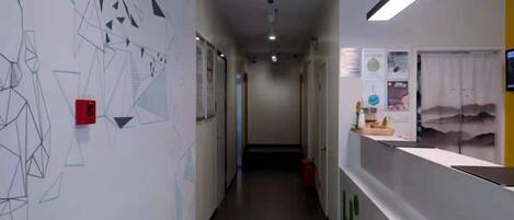 A hallway with geometric wall art, a reception desk, and a door at the end.