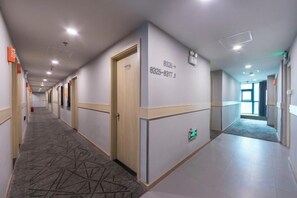 A hotel corridor with doors, emergency exit signs, and a patterned carpet. - Jitai Hotel (Shanghai Dahua 3rd Road Subway Station) (Shanghai)