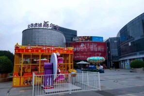 A food stall with a traditional design, a large cylindrical structure in the background, and a modern building with signage. - Jitai Hotel (Shanghai Dahua 3rd Road Subway Station) (Shanghai)