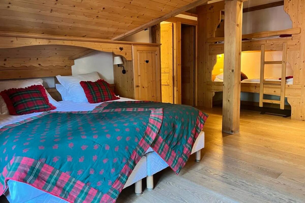A cozy wooden cabin bedroom with a bed, a nightstand, and a wooden ladder.
