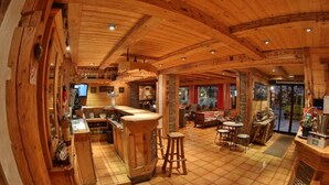 A wooden interior with a bar area, seating, and a fireplace. - Fleur Des Neiges  (Morzine)