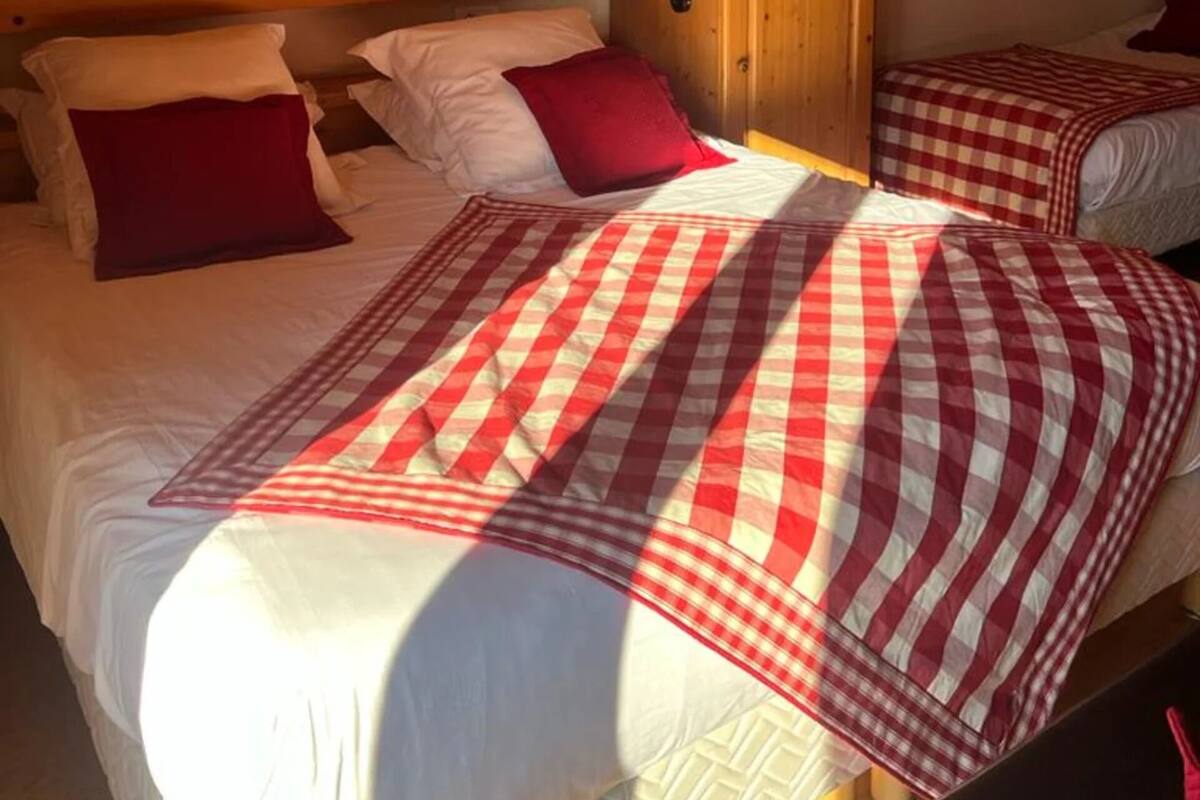 A wooden cabin bedroom with two beds, each with red and white checkered bedding.