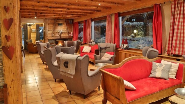 A cozy, log-floored room with multiple seating areas, including sofas and armchairs, arranged around a central fireplace. - Fleur Des Neiges  (Morzine)