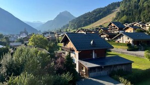 A mountainous village with traditional wooden houses, a clear sky, and lush greenery. - Fleur Des Neiges  (Morzine)