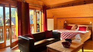 A wooden cabin room with a bed, a sofa, and a table. - Fleur Des Neiges  (Morzine)