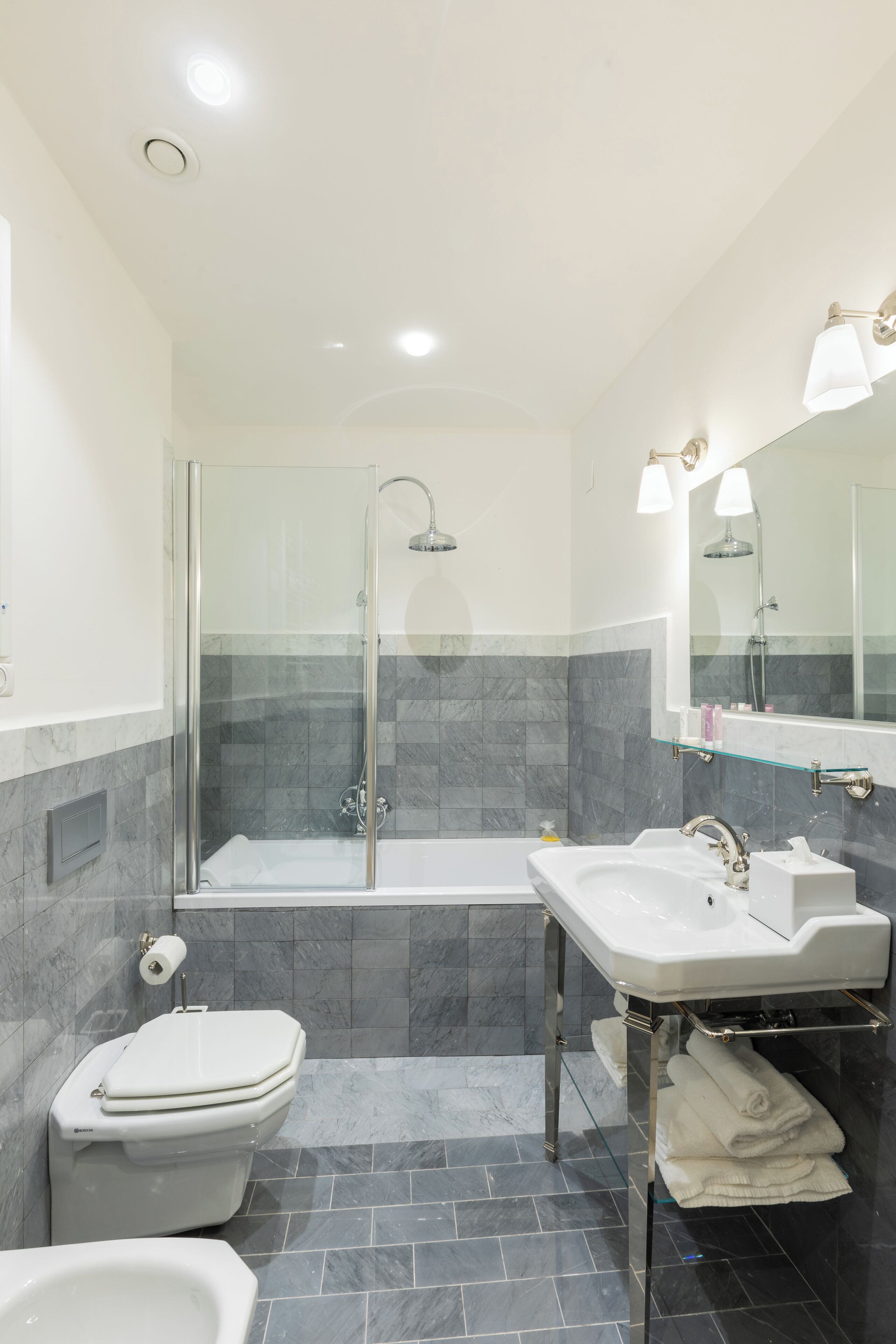 A modern bathroom with a glass-enclosed shower, a white sink, and a toilet.