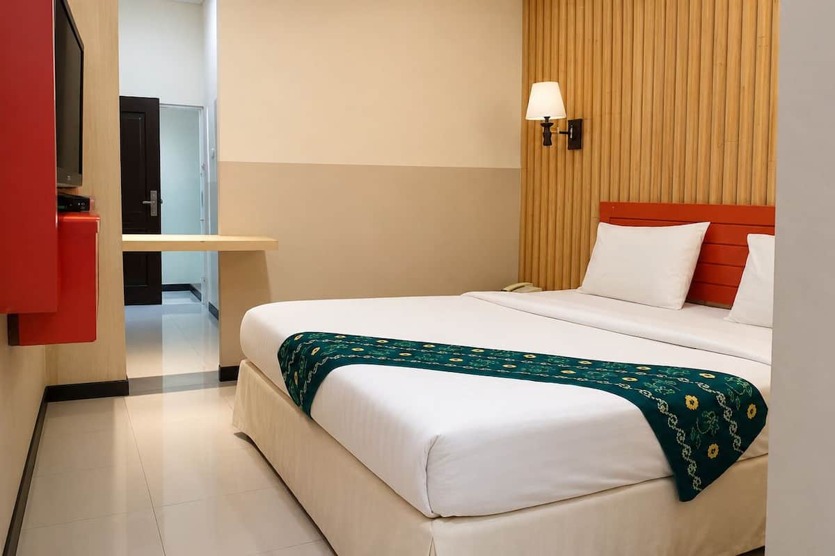 Habitación de hotel con cama, mesita de noche, lámpara y pared de paneles de madera.
