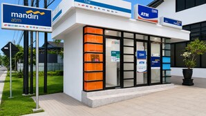 A mandiri ATM with a glass facade, a BNI sign, and a potted plant outside. - QUEEN CITY HOTEL (Banjarmasin)