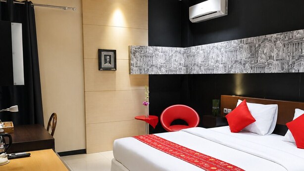 A modern hotel room with a bed, a desk, and a red chair. - QUEEN CITY HOTEL (Banjarmasin)