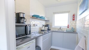 A compact kitchen with a microwave, coffee maker, toaster, and a sink. - Chalet 38 (Great Yarmouth)