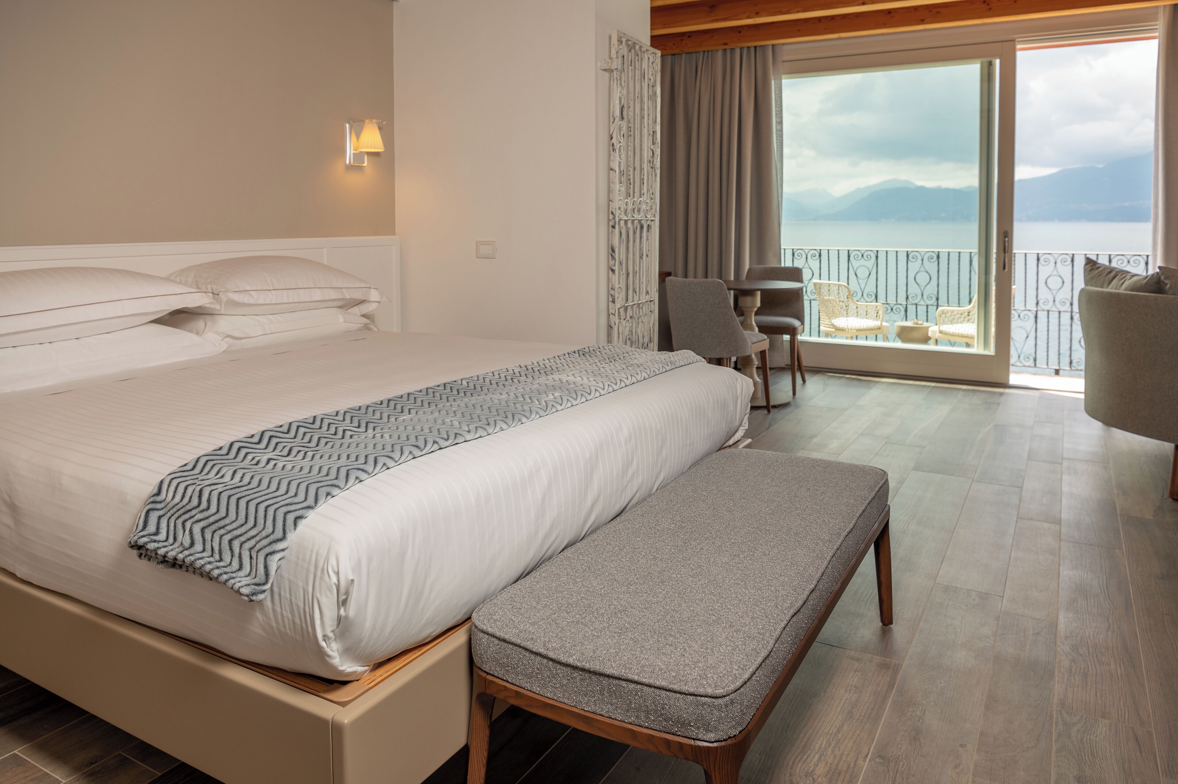Ein Hotelzimmer mit Bett, Sitzbank und einem Balkon mit Stühlen und Tisch.
