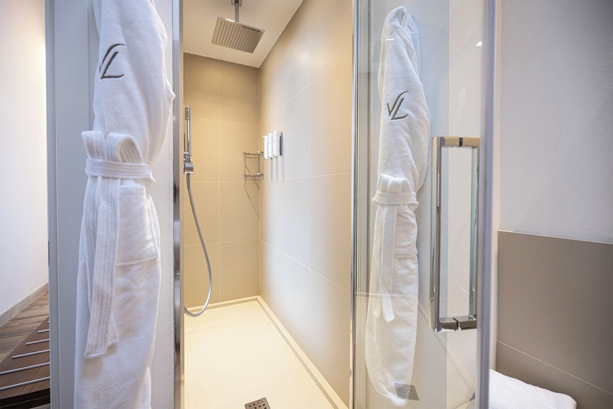 A glass-enclosed shower area with a handheld showerhead and a glass door.