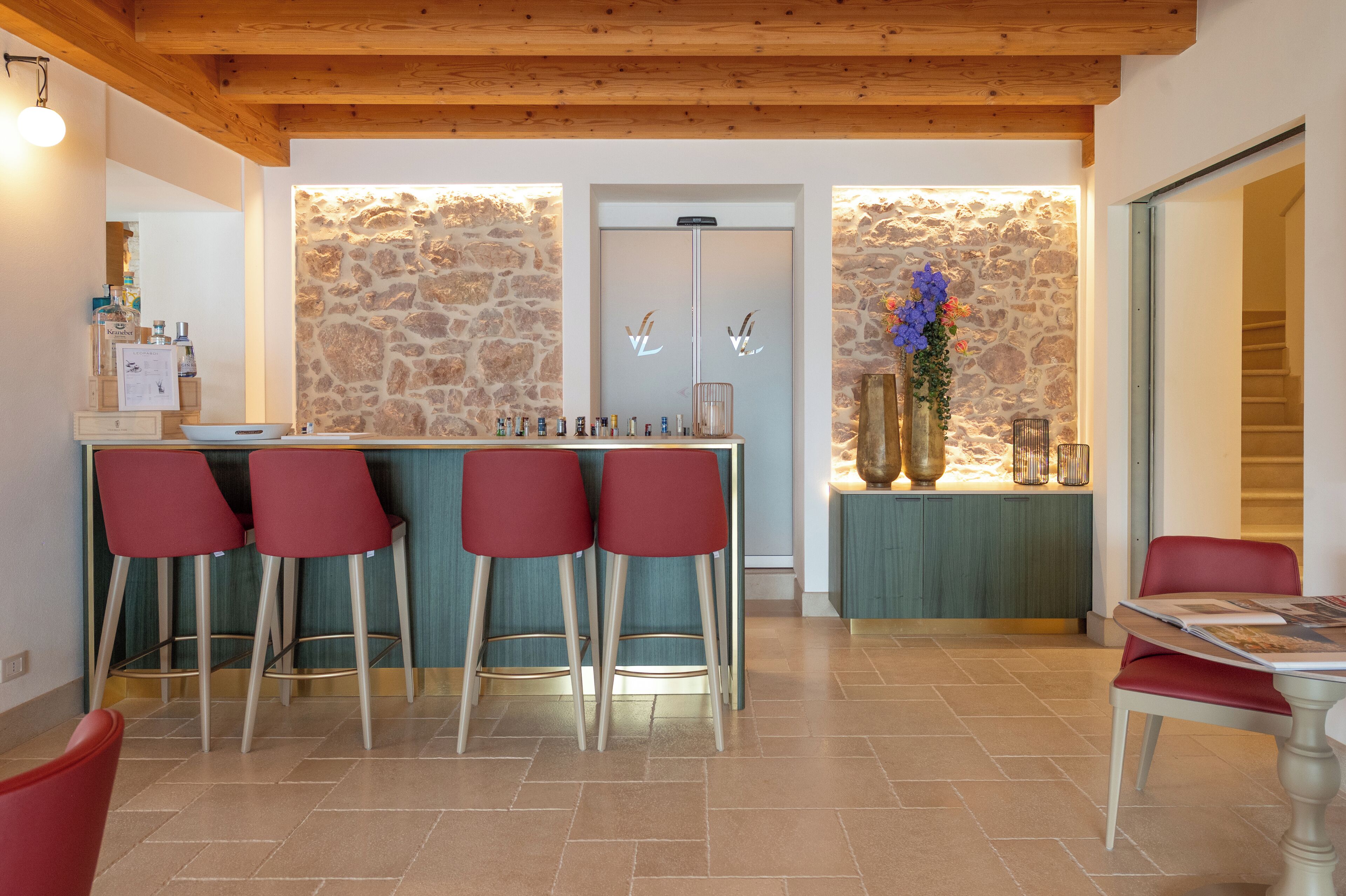 A bar area with stools, a stone wall, and a wooden ceiling.