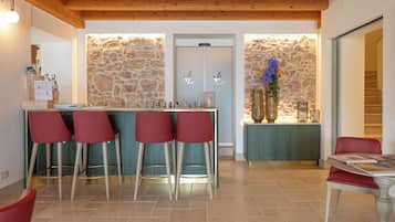 A bar area with stools, a stone wall, and a wooden ceiling.