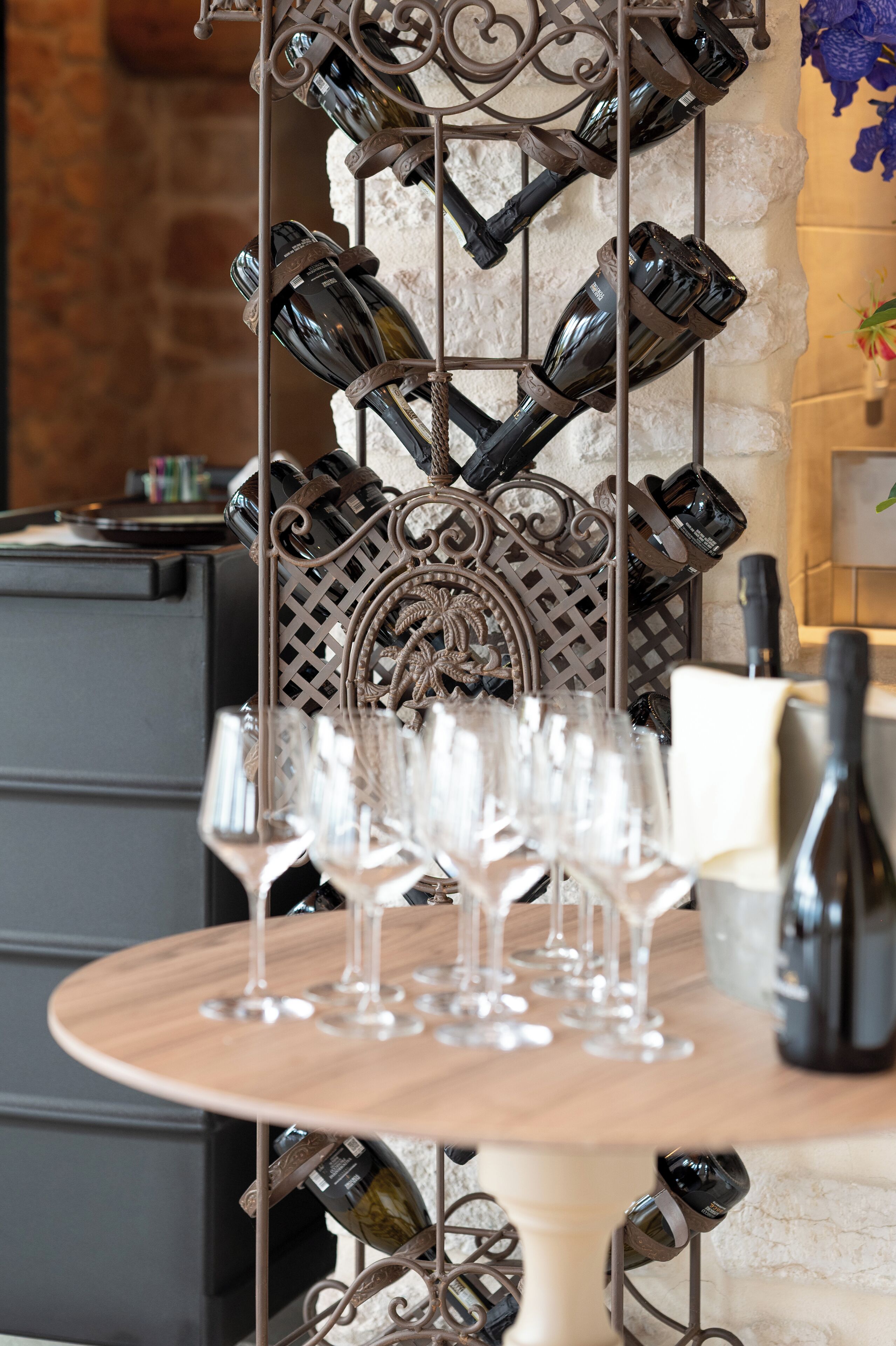 A wine rack with bottles and glasses on a table.
