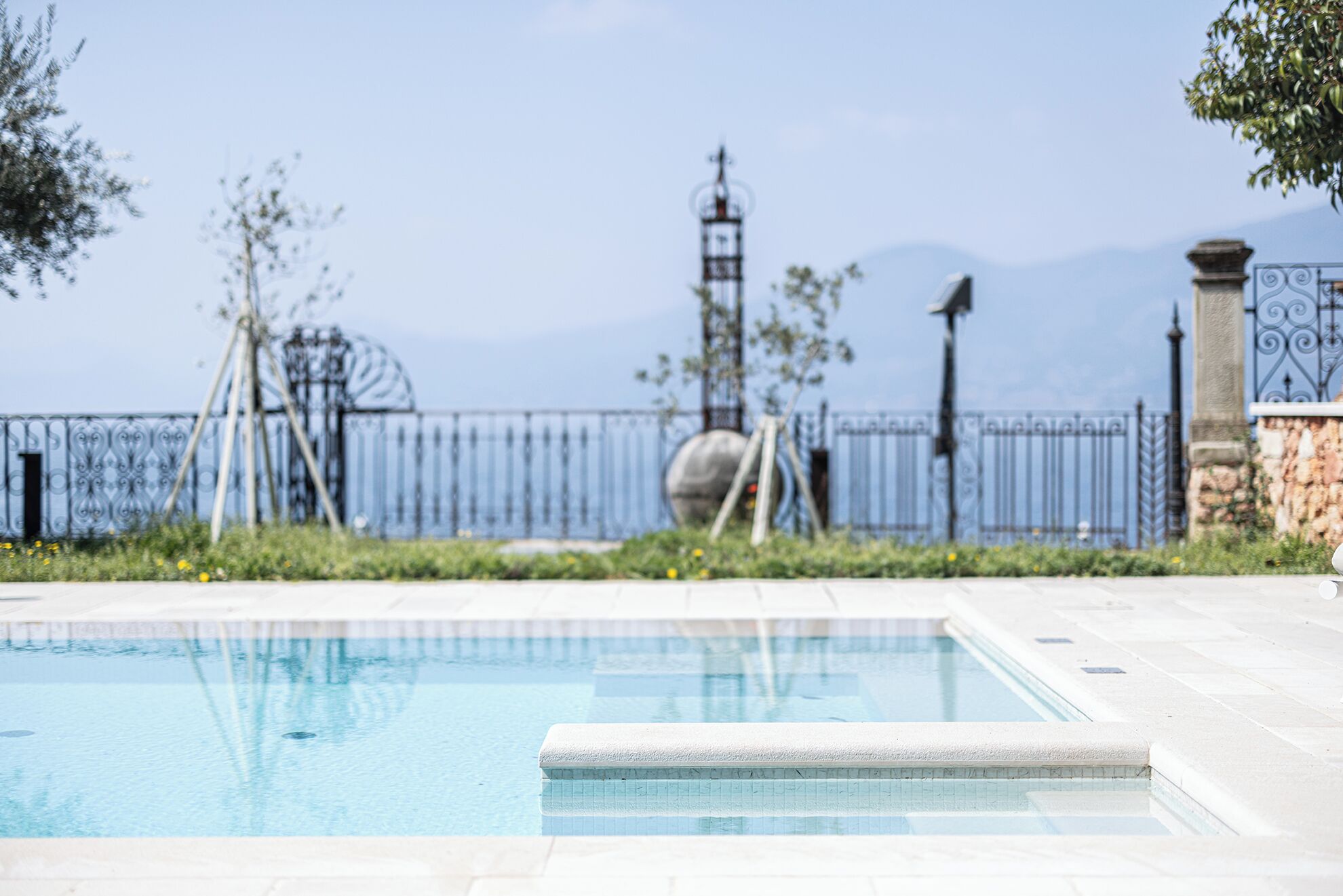 Une piscine offrant une vue dégagée sur une clôture en métal et un mur de pierre en arrière-plan.