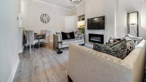 Una sala de estar con sofá, sillones, televisor y chimenea.