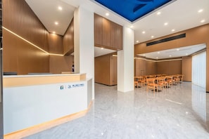 A hotel reception area with a modern design, featuring a reception desk, seating area, and a conference room.