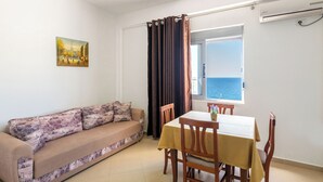 Una habitación con sofá, una mesa de comedor y vistas al mar.