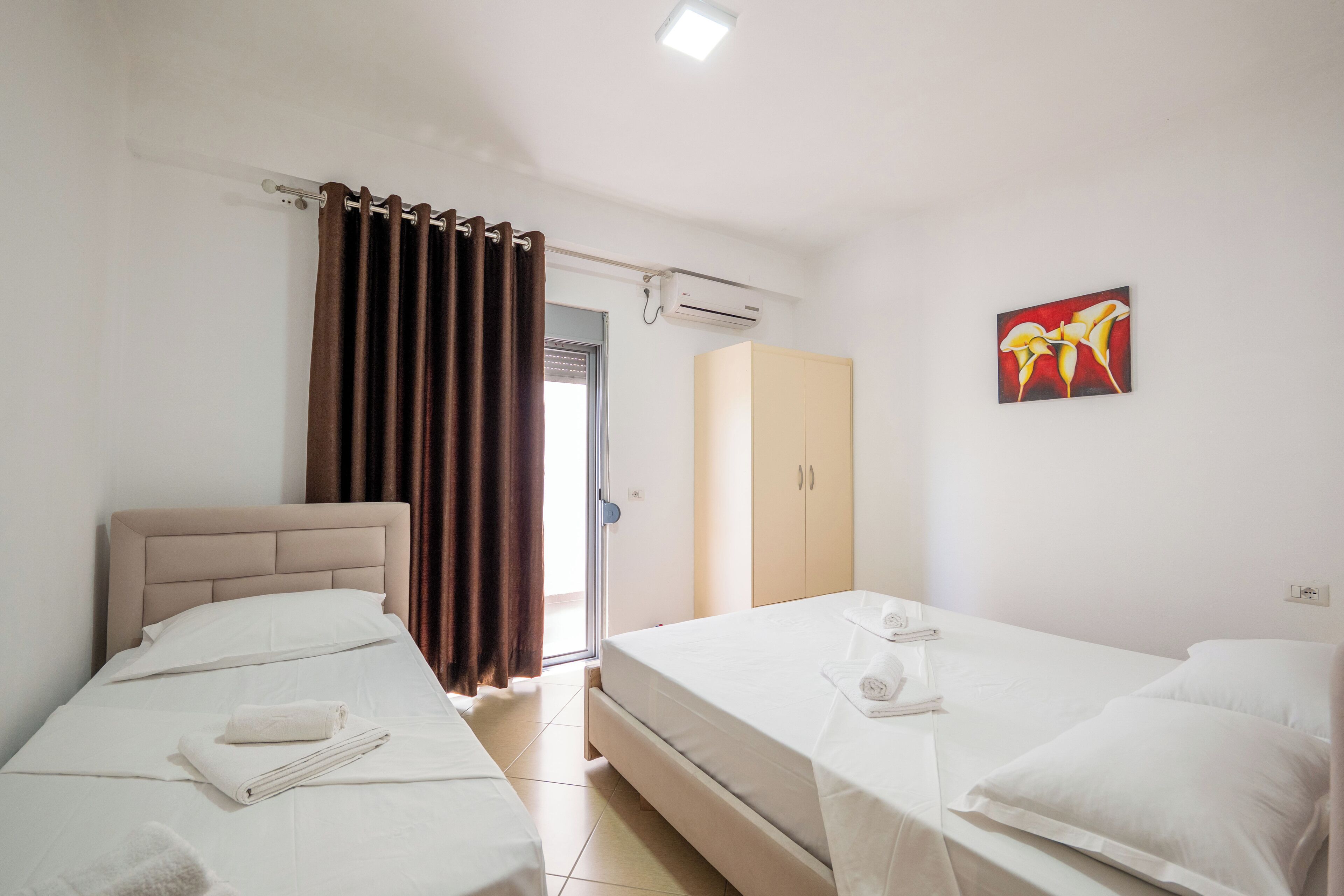 Ein Hotelzimmer mit zwei Einzelbetten, einem Kleiderschrank, einer Klimaanlage und einem Bild an der Wand.