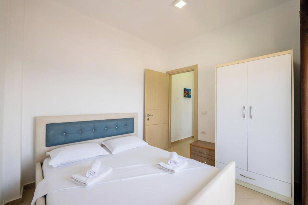 A hotel room with a bed, a wardrobe, and a mirror.