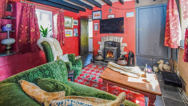 Un salon chaleureux avec un canapé vert, une cheminée et un tapis aux motifs rouges et verts.
