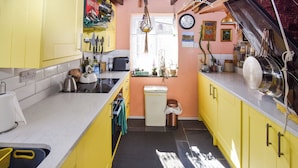 Une cuisine avec des meubles de couleur jaune, un évier et divers appareils de cuisine.