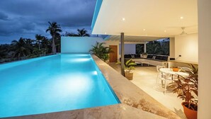 Un área de piscina moderna al aire libre con zona de estar y comedor.