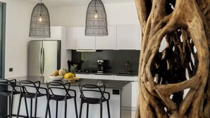 Una cocina moderna con una isla central, taburetes altos negros y dos lámparas colgantes.