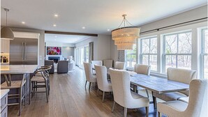 A spacious kitchen with a large island, modern appliances, and ample natural light from large windows. - Brand New Spacious Luxury Home on Edgartown Great Pond with Pool and Spa (Edgartown)