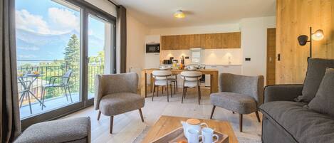 Una sala de estar moderna con comedor, cocina y balcón con vistas a la montaña.