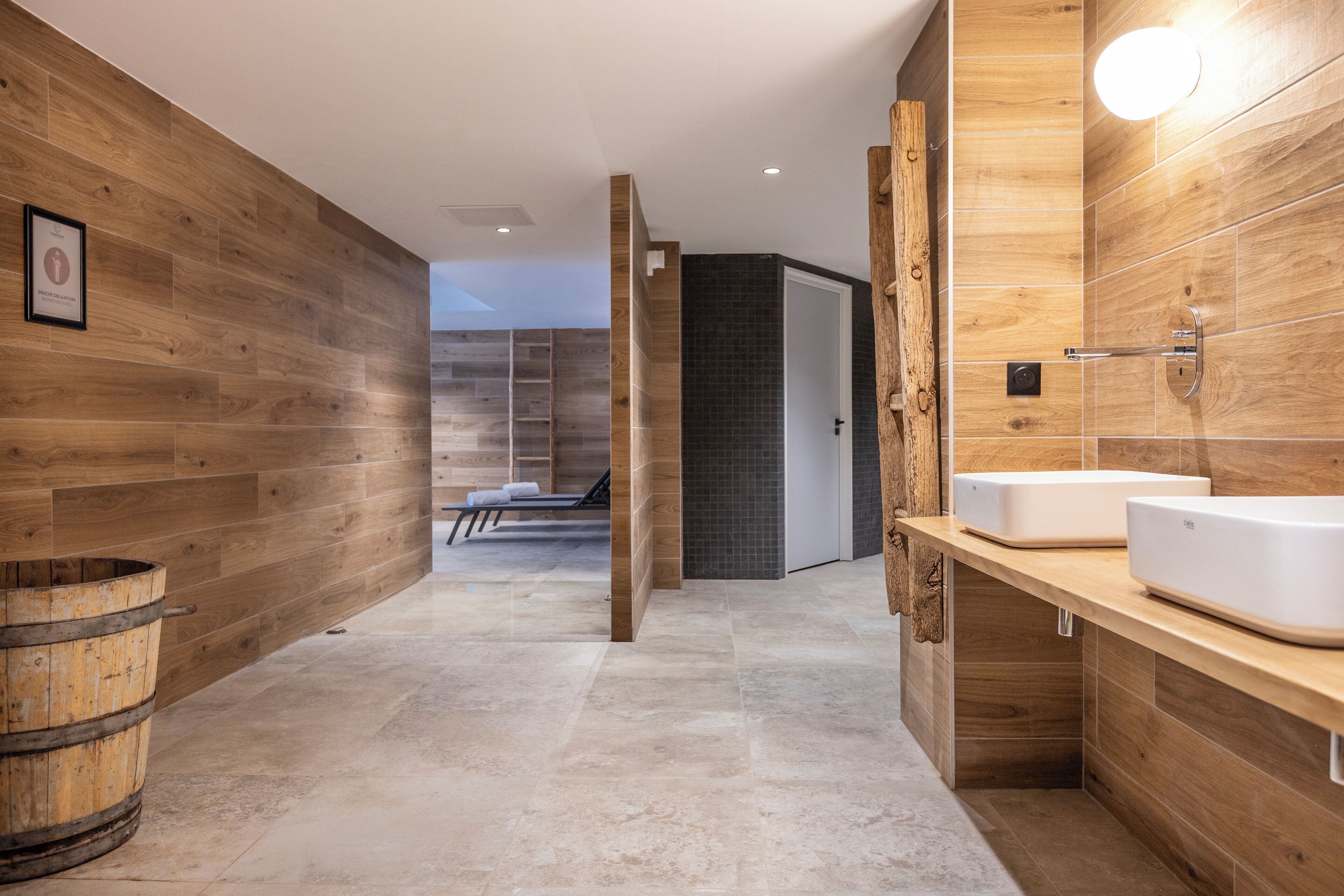Un baño moderno con paredes de madera, un espejo grande y un tocador de madera.