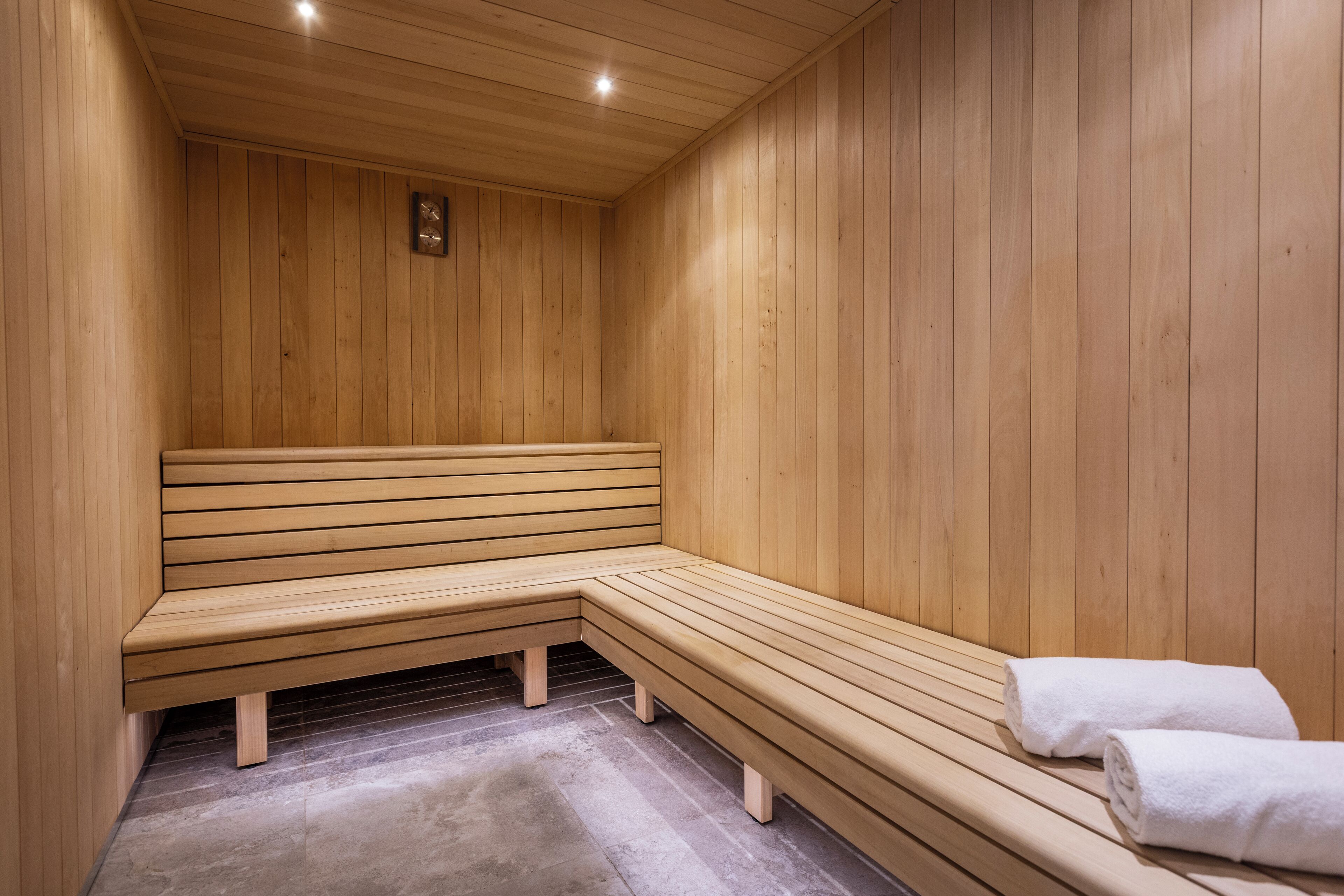 A sauna with wooden benches and a bench seat, a towel on the right, and a small plaque on the wall.