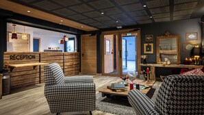 A reception area with houndstooth patterned chairs, a wooden reception desk, and a ceiling with a grid pattern. - TERRESENS - Les Sources de Canopée  (Saint-Gervais-les-Bains)