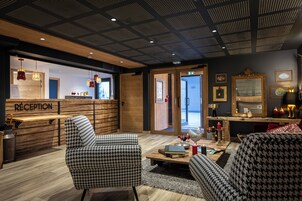 Un área de recepción con sillones estampados de piedritas, un mostrador de madera y un techo con diseño de cuadrícula.
